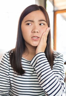 a woman holding her cheek due to tooth pain