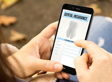 Patient looking at dental insurance form on phone outside