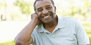 Man with mustache smiling outside
