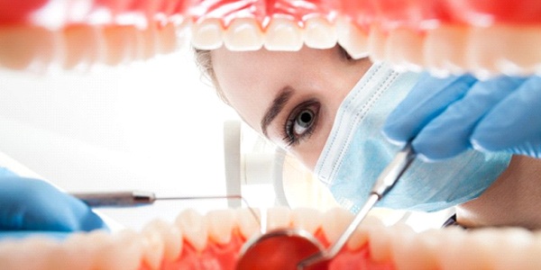 A dentist examining a person’s mouth.