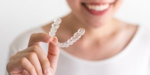 person holding an Invisalign aligner in their hand 