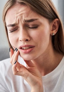 a woman experiencing tooth pain and needing emergency dentistry
