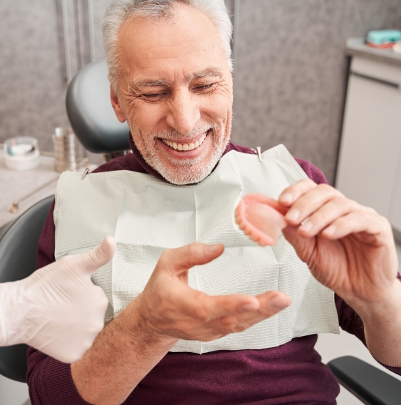 Hand holding full denture