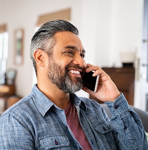 Man smiling while talking on phone at home