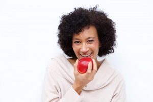 woman eating a red apple with dentures in Glastonbury