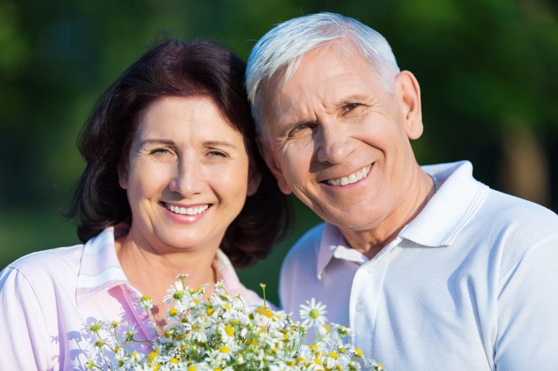 couple with dentures smiling and holding flowers