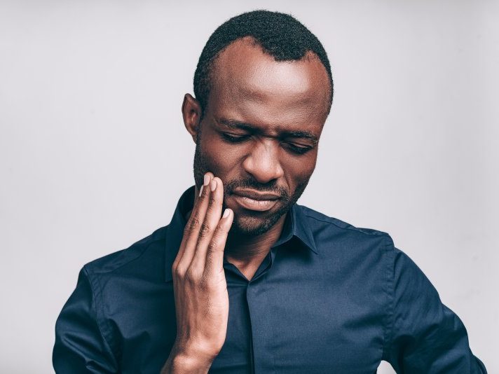 person with a toothache holding their cheek