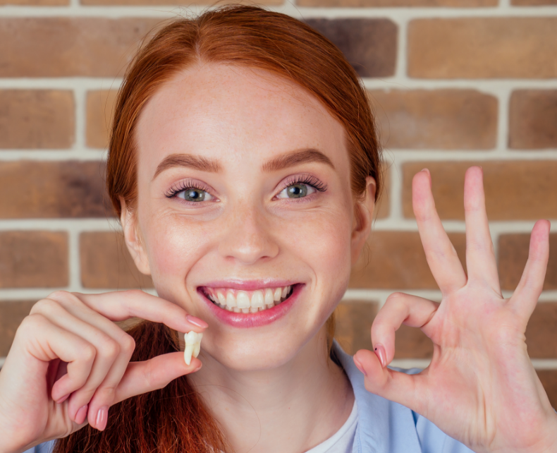 Woman holding tooth and smiling