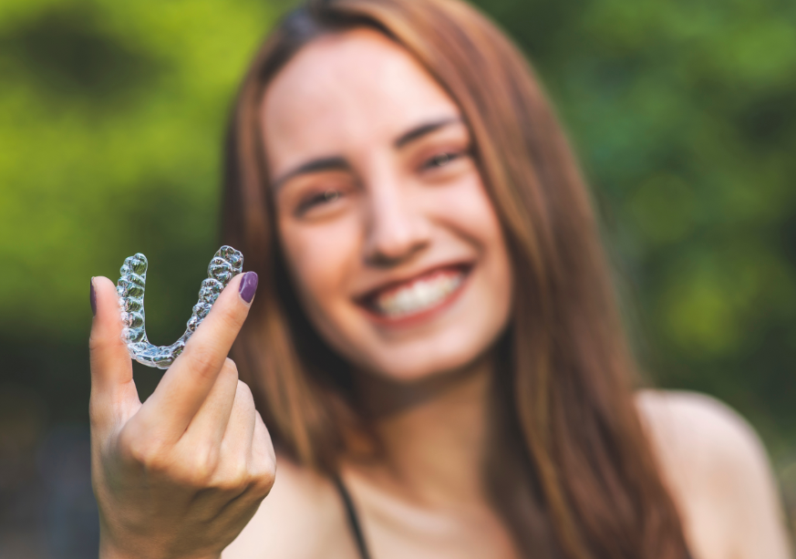 Woman holding up clear aligner